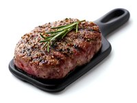 Juicy grilled ribeye steak seasoned with herbs and spices on black cast iron serving board with fresh rosemary garnish against white background.