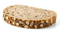Slice of multigrain seeded bread with sunflower seeds and oats isolated on white background for healthy eating and bakery concepts.