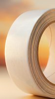 White adhesive tape roll close-up with warm orange background for construction, packaging, repair and maintenance projects in workshop or office.