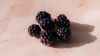 Fresh ripe blackberries cluster on soft pink surface casting gentle shadows. Organic summer fruit harvest for healthy eating and culinary recipes.