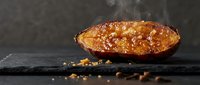 Caramelized crème brûlée dessert with golden sugar crust on dark slate surface with vanilla beans and caramel crystals for gourmet culinary presentations.