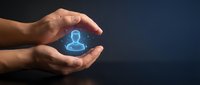 Protective hands surrounding glowing blue user profile icon representing digital security, data protection and customer care in modern business technology.