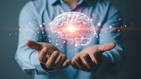 Professional man in blue shirt holding glowing brain hologram with neural network connections representing artificial intelligence and innovation.