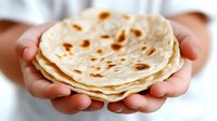 Fresh homemade flour tortillas held in cupped hands, soft flatbread stack with golden brown spots, traditional Mexican cuisine preparation ready for tacos.