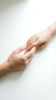 Two hands reaching toward each other in gentle touch against clean white background symbolizing connection, support, help and human compassion.
