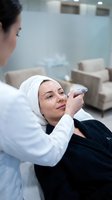Professional dermatologist marking facial injection points on female patient for cosmetic procedure in modern medical clinic setting.