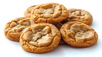 Fresh baked golden brown cookies with crispy edges and soft centers, scattered on white surface. Close up view shows chewy texture and crackled tops.