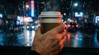 Coffee cup held in hand against blurred neon city lights at night, suitable for beverage, urban lifestyle, and technology marketing campaigns.