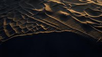 Golden sand dunes with dramatic shadows and rippled textures creating abstract desert landscape patterns in warm sunlight.