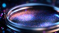 Vibrant cosmic glitter texture with pink and blue sparkles in glass container against dark background creates magical ethereal mood for creative designs.