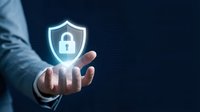 Businessman in blue shirt holding glowing shield with padlock icon, representing cybersecurity, data protection, and digital safety solutions for enterprise networks.