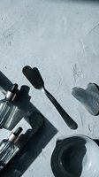 Kitchen utensils and cookware casting dramatic shadows on textured concrete surface for culinary design projects.