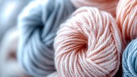 Soft wool yarn balls in pastel pink and blue colors with selective focus macro shot showing detailed texture of twisted threads. For crafting and knitting projects.
