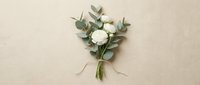 Small white rose bouquet with eucalyptus leaves arranged on neutral beige background for wedding invitations and romantic greeting cards.