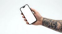 Tattooed hand holding smartphone with blank white screen mockup for app presentation and mobile interface design on neutral background.