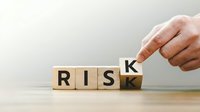 Hand placing wooden letter K to complete RISK word on wooden blocks, business risk management and decision making concept for corporate strategy.