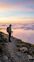 Male hiker with backpack and trekking poles standing on mountain trail at sunrise above clouds. Adventure travel and outdoor hiking concept for tourism and wellness campaigns.