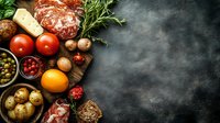 Fresh ingredients and Mediterranean food composition with meat, vegetables, herbs, and spices on dark rustic background with copy space for menu or recipe.