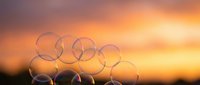Soap bubbles floating against warm sunset sky with orange and pink hues creating dreamy atmospheric background for relaxation and mindfulness concepts.