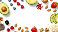 Fresh superfood ingredients frame on white background with avocado berries nuts seeds and oats for healthy nutrition meal planning and diet concepts.