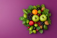 Fresh colorful fruits arranged in circular composition with green leaves on purple background, overhead view. Healthy eating and natural food concept.