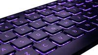 Close-up of illuminated purple keyboard with glowing keys for gaming, typing, and computer work on isolated white background.