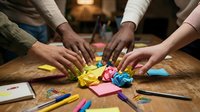 Diverse hands collaborating on creative brainstorming session with colorful sticky notes and markers on wooden table in modern office workspace.