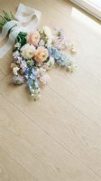 Delicate spring bouquet with ranunculus and eucalyptus wrapped in white ribbon on light wooden floor with natural sunlight for wedding decor.
