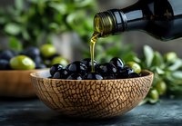 Fresh black olives in rustic ceramic bowl with pouring extra virgin olive oil, green olives and leaves in background on dark surface, Mediterranean cuisine.