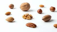 Assorted nuts and kernels scattered on white background including walnut, almond, hazelnut and pecan for healthy snacking and cooking ingredients.