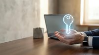 Business professional holding glowing key hologram above palm in modern office workspace representing security solutions and digital access control.