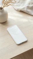 White smartphone mockup on wooden desk with pampas grass in ceramic vase and linen fabric creating minimalist workspace scene for app presentation.