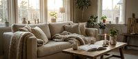Cozy modern living room interior with beige sectional sofa, wooden coffee table, soft throws and pillows. Warm natural lighting creates inviting atmosphere.