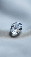 Brilliant cut diamond gemstone with sparkling facets on elegant gray surface for luxury jewelry and engagement ring designs.