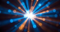 Bright starburst light explosion with colorful bokeh effects and radial beams creating dynamic energy burst on dark background for presentations.