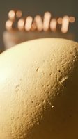 Close-up of a natural brown egg with textured shell surface, warm bokeh Easter lettering glowing softly in the background, holiday concept.