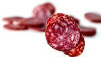 Sliced salami sausage with visible fat marbling on white background, isolated for food photography and culinary design projects.