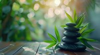 Zen stones pyramid with bamboo leaves on wooden surface against blurred natural bokeh background, perfect for spa, meditation, and wellness designs.