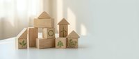 Wooden building blocks with eco-friendly green symbols arranged on white surface. Sustainable construction and environmental awareness concept for design.