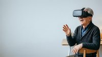 Senior man wearing virtual reality headset, experiencing immersive VR technology and digital interaction in studio setting.