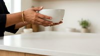 Senior male professional with dark skin tone holding empty ceramic bowl at modern office desk, representing hospitality, service, or business concepts.