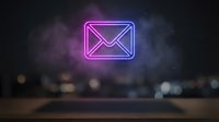 Glowing pink neon email envelope icon floating above blurred city lights at night. Digital communication concept for marketing and business correspondence.