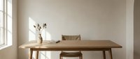 Minimalist wooden dining table with ceramic vase and dried flowers in bright modern interior with natural light from large window.
