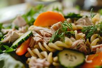 Fresh pasta salad with shredded chicken, cucumber slices, baby carrots, and dill garnish in macro view, highlighting vibrant colors and textures for food service.