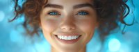Young woman with natural curly hair and bright smile against blue bokeh background. Close up portrait showing radiant, healthy skin and white teeth.
