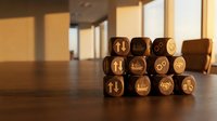 Wooden blocks with business and finance icons arranged on desk surface with warm lighting and blurred office background.