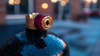 Vintage style camera on wet surface with bokeh lights in background, creating atmospheric moody composition with water drops and evening urban ambiance.