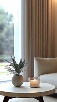 Minimalist living room corner with round coffee table, glowing candle and small fern plant in spherical pot near window. Cozy modern interior design setting.
