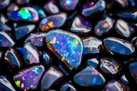 Vibrant black opals displaying brilliant blue, purple and rainbow fire patterns in macro photography, showcasing natural iridescent play-of-color on dark background.