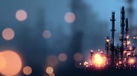 Industrial oil refinery silhouette at dusk with glowing lights and bokeh effect creating atmospheric mood for energy and petrochemical industry concepts.